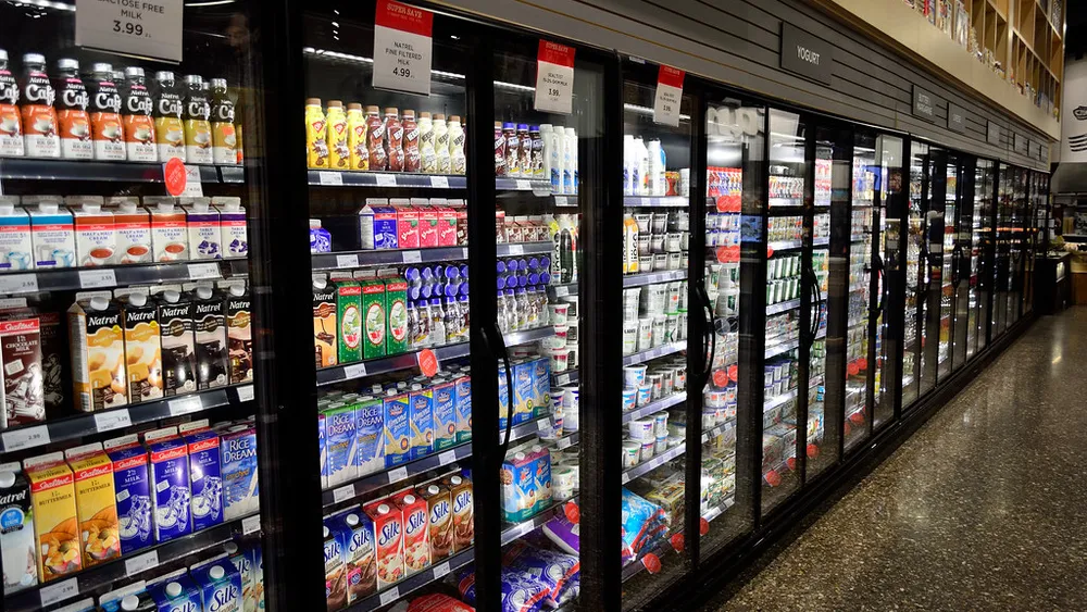 A long row of glass-door reach-in refrigerated cases in a supermarket.