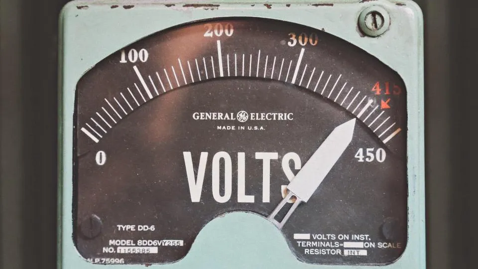 An analog electrical panel meter measuring volts.